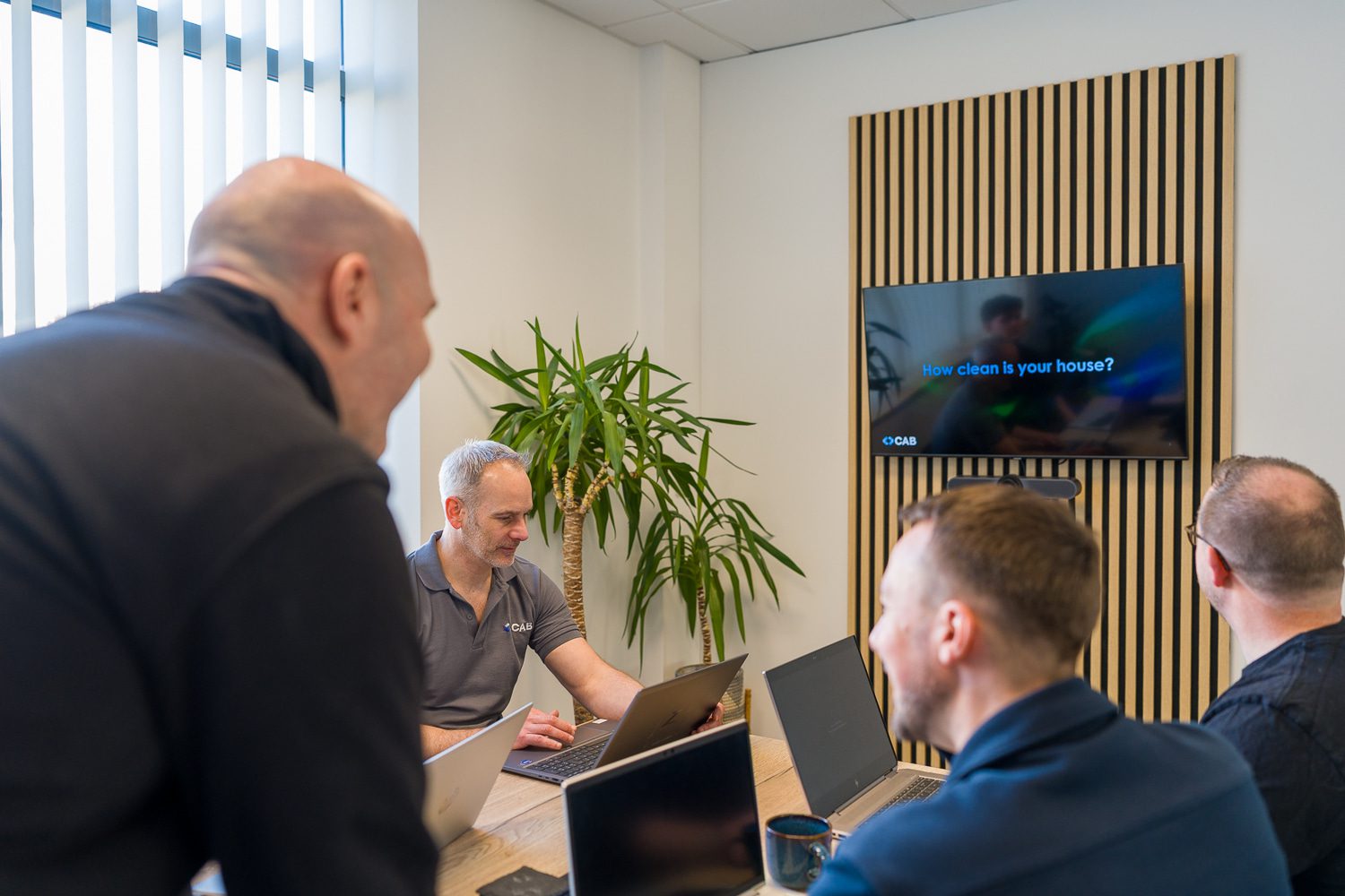 CAB IT team gathered around their laptops smiling in the meeting room